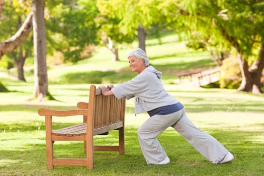 Senior woman doing her stretches in the park during the summer