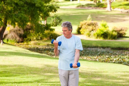 Elderly man doing his exercises in the park during the summer