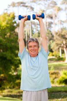 Mature man doing his exercises in the park during the summer