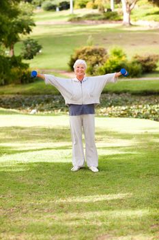 Mature woman doing her exercises in the park during the summer