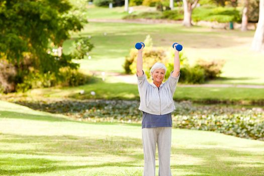 Mature woman doing her exercises in the park during the summer