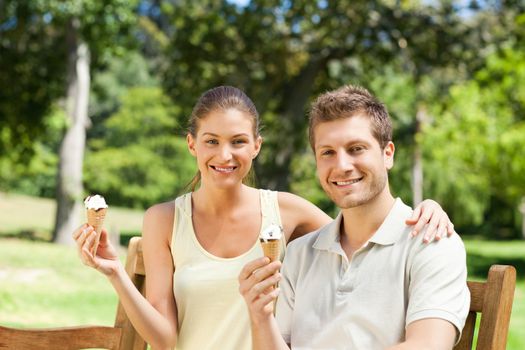 Couple eating an ice cream in the park during the summer