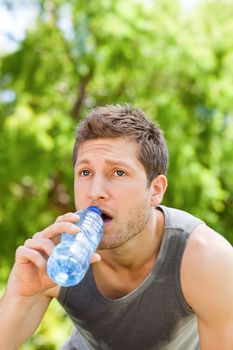 Sporty man drinking water in the park during the summer