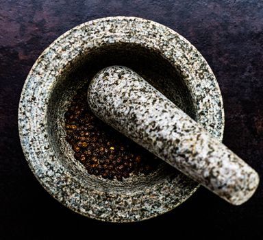 Mortar bowl and pestle on dark stone surface