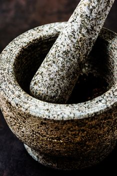 Mortar bowl and pestle on dark stone surface