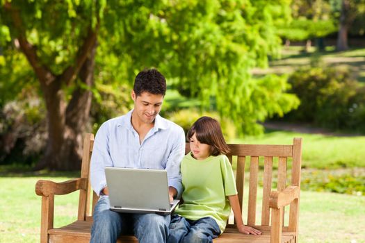 Son with his father looking at their laptop during the summer