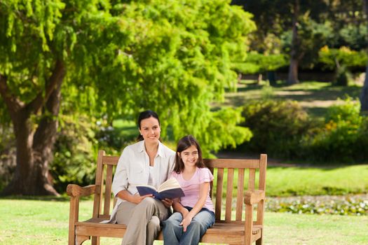 Mother and her daughter reading a book during the summer