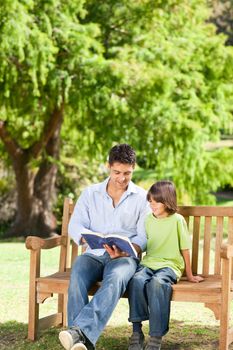 Father with his son reading a book during the summer