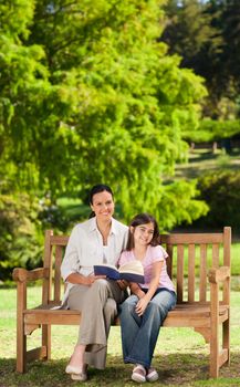 Mother and her daughter reading a book during the summer