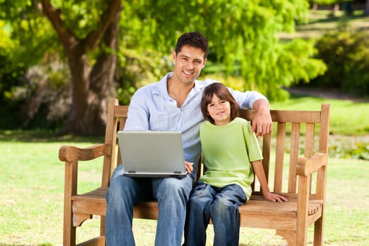 Son with his father looking at their laptop during the summer