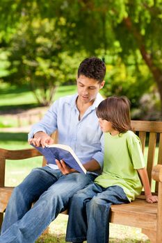 Father with his son reading a book during the summer