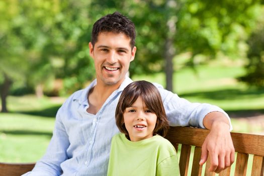 Son with his father on the bench during the summer