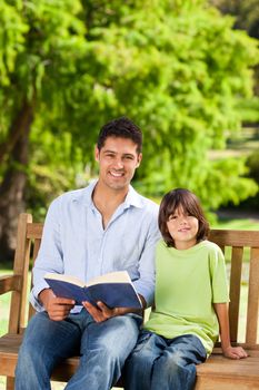 Son with his father reading a book during the summer