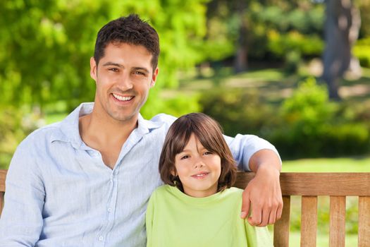 Son with his father on the bench during the summer