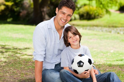 Father and his son with their ball in the park during the summer