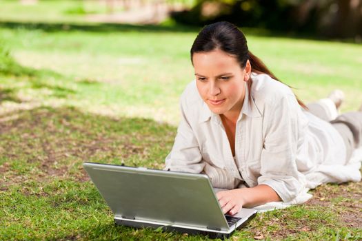 Woman working on her laptop in the park during the summer