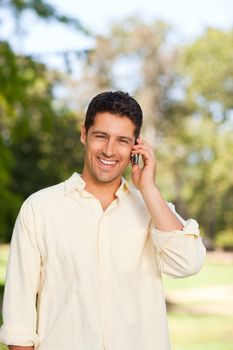 Handsome man phoning in the park during the summer