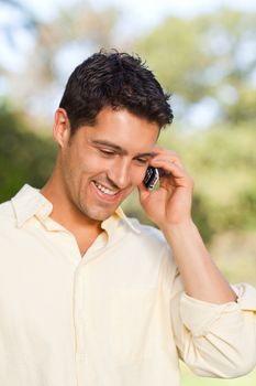 Handsome man phoning in the park during the summer