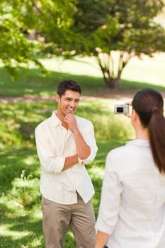 Woman taking a photo of her boyfriend in a park