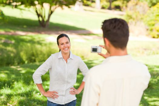 Man taking a photo of his girlfriend in a park