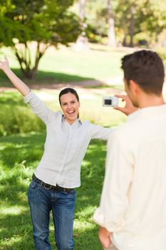 Man taking a photo of his girlfriend in a park