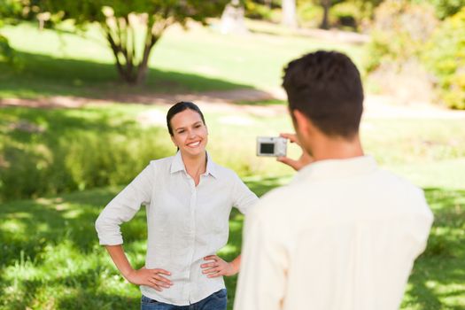 Man taking a photo of his girlfriend in a park