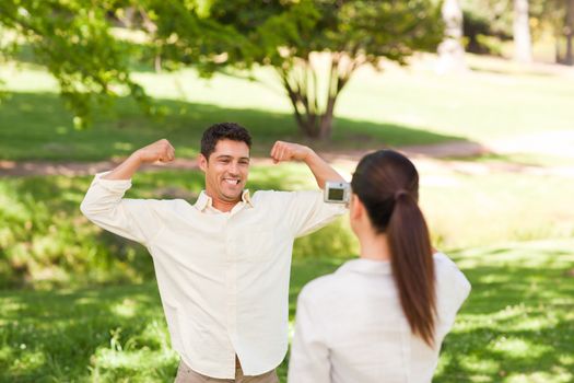 Woman taking a photo of her boyfriend in a park