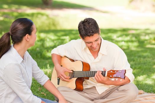 Romantic man playing guitar for his wife in a park