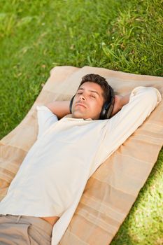 Young man listening to music in the park durrig the summer