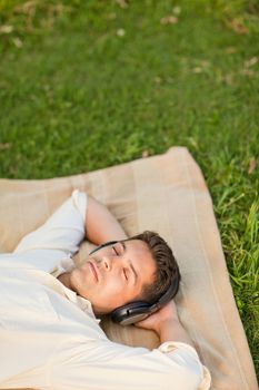 Young man listening to music in the park durrig the summer