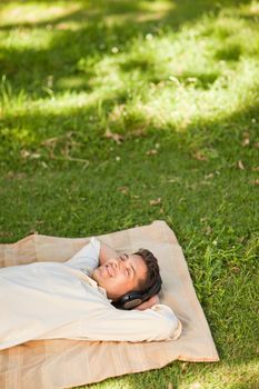 Young man listening to music in the park durrig the summer