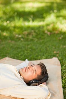 Young man listening to music in the park durrig the summer