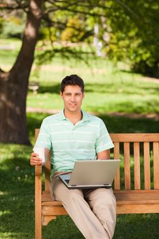 Man working on his laptop in the park during the summer 