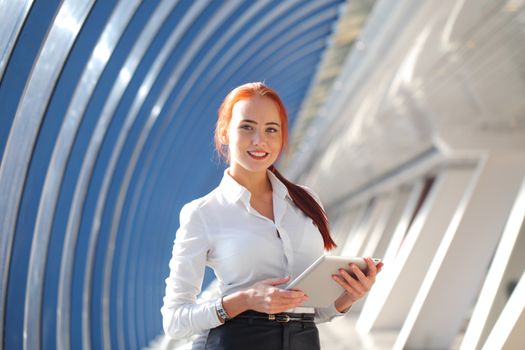 Beautiful modern businesswoman holding tablet computer inside modern building