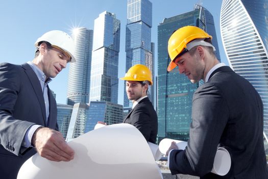 Architects with blueprint at skyscrapers background