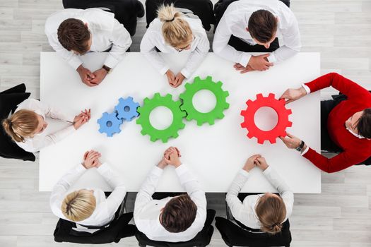 Business problem solution, mechanism of business, teamwork concept, business team sitting around white table with cogs