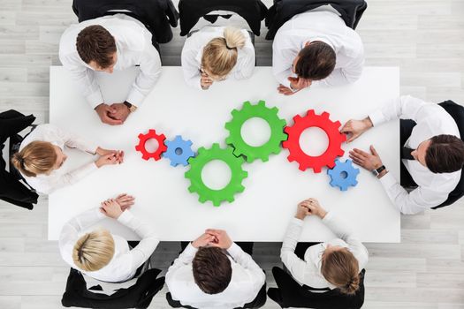 Business problem solution, mechanism of business, teamwork concept, business team sitting around white table with cogs