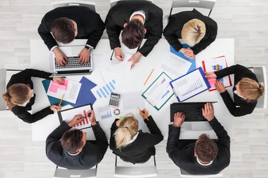 Business people work with statistics documents with tables and diagrams sitting around the table