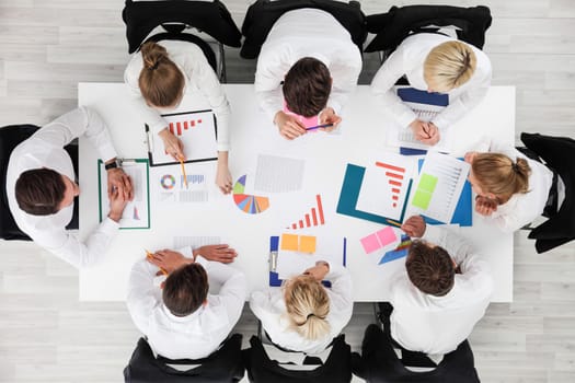 Business people work with statistics documents with tables and diagrams sitting around the table