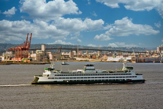 A large ferry crossing the bay past a shipping and freight yard