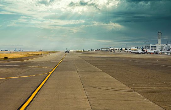 View down a large commercial runway with a jet taking off