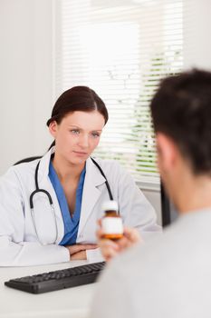 A female doctor looking at patient with can of pills