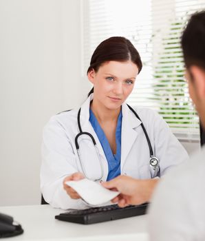 A kind female doctor is giving a patient a prescription