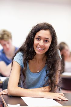 Portrait of a happy student working on an assignment in a classroom