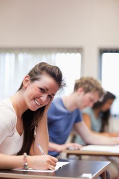 Portrait of a smiling woman writing in a classroom