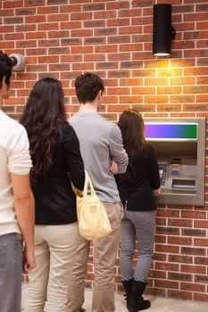 Portrait of people queuing to withdraw cash at an ATM