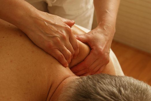A masseuse giving massage to a middle age man at a spa in bangkok. This image was taken on June 2014.