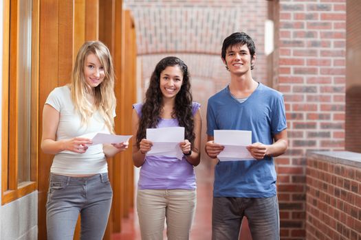 Smiling students holding a piece of paper in a corridor