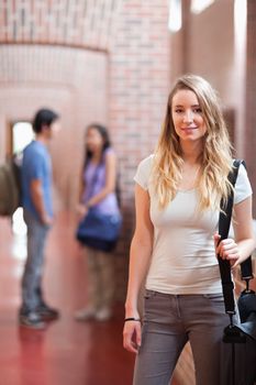 Portrait of a student posing while her friends are talking in a corridor