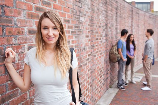 Beautiful student posing while her friends are talking outside a building